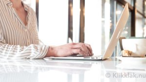 Schrijver druk aan het werk achter de laptop